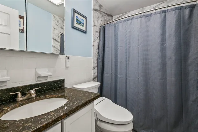 a bathroom with a granite countertop sink toilet and a mirror
