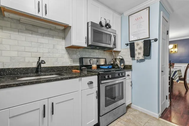 a kitchen with stainless steel appliances granite countertop white cabinets a stove top oven a sink and dishwasher