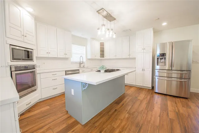 a kitchen with stainless steel appliances a refrigerator a stove a sink and white cabinets