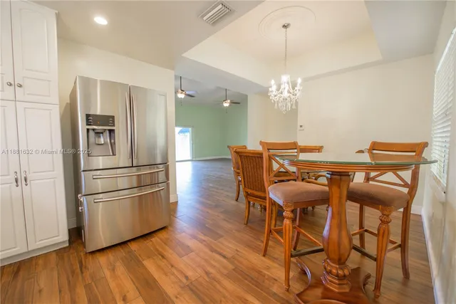 a kitchen with stainless steel appliances granite countertop a refrigerator a stove a microwave oven a dining table and chairs with wooden floor