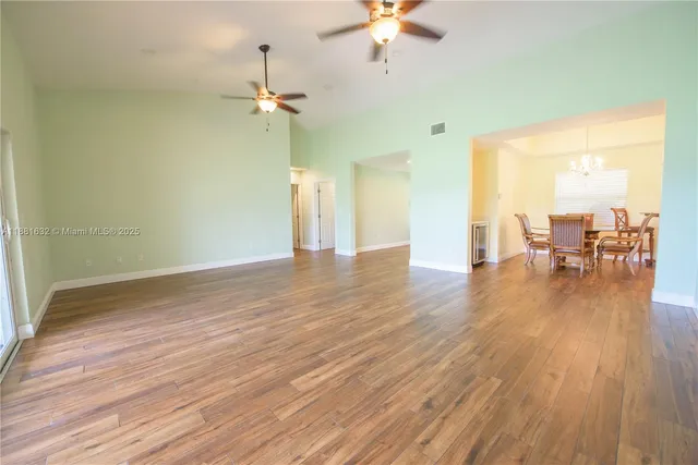 a view of a livingroom with furniture wooden floor a ceiling fan and windows