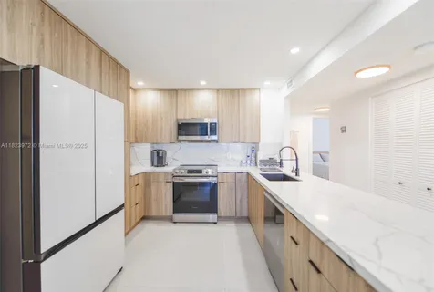 a large kitchen with a large counter top stainless steel appliances and cabinets