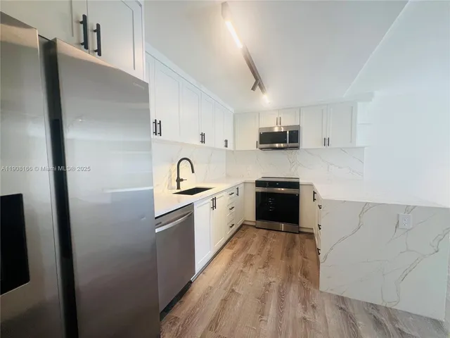 a kitchen with granite countertop a refrigerator stove top oven and sink