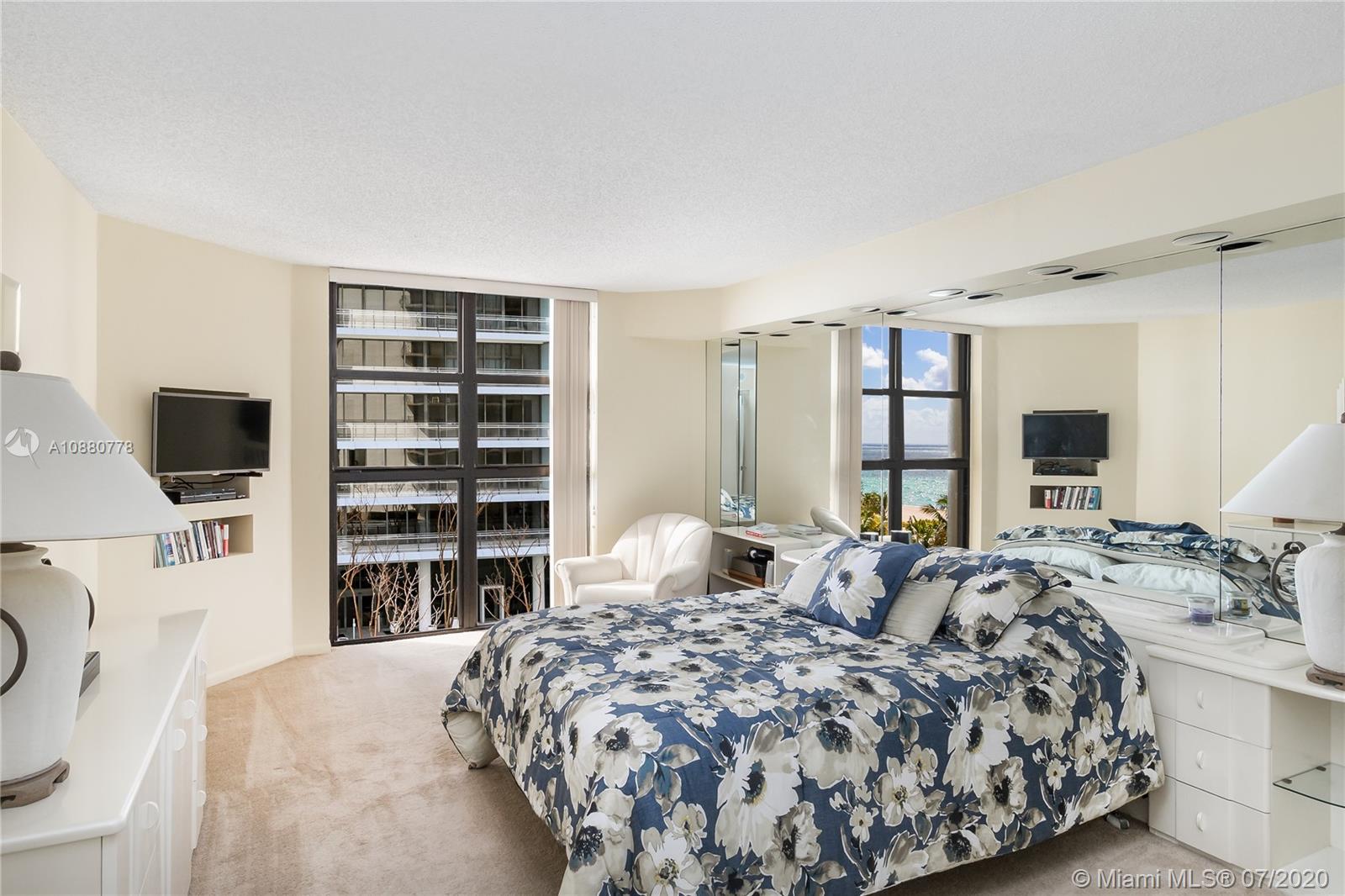 8777 Collins Avenue, Unit 611 Surfside, FL 33154 - Photo 15 of 22 a bedroom with a large bed and a flat tv screen on dresser