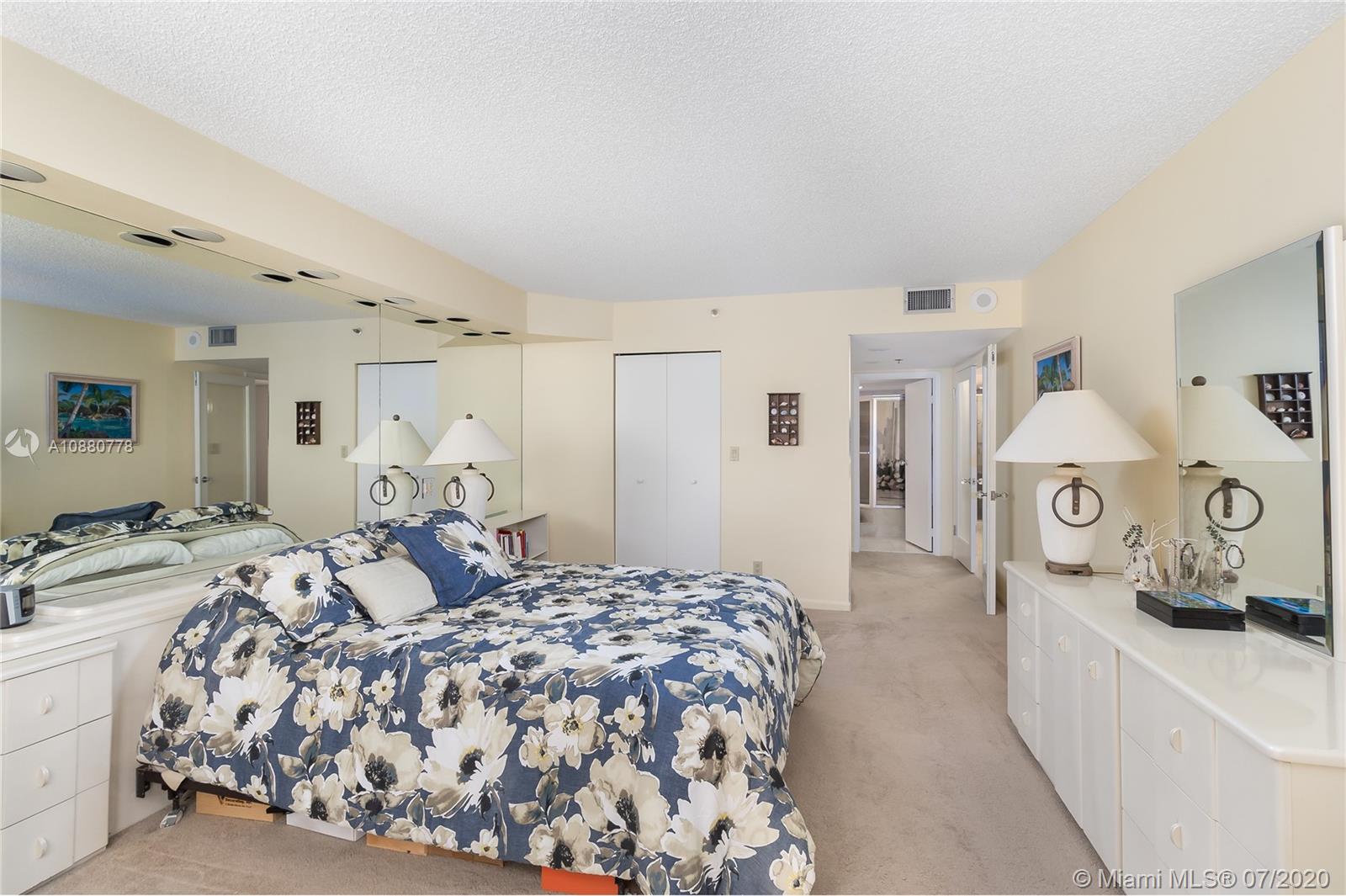 8777 Collins Avenue, Unit 611 Surfside, FL 33154 - Photo 17 of 22 a bedroom with a bed and a lamp on the dresser