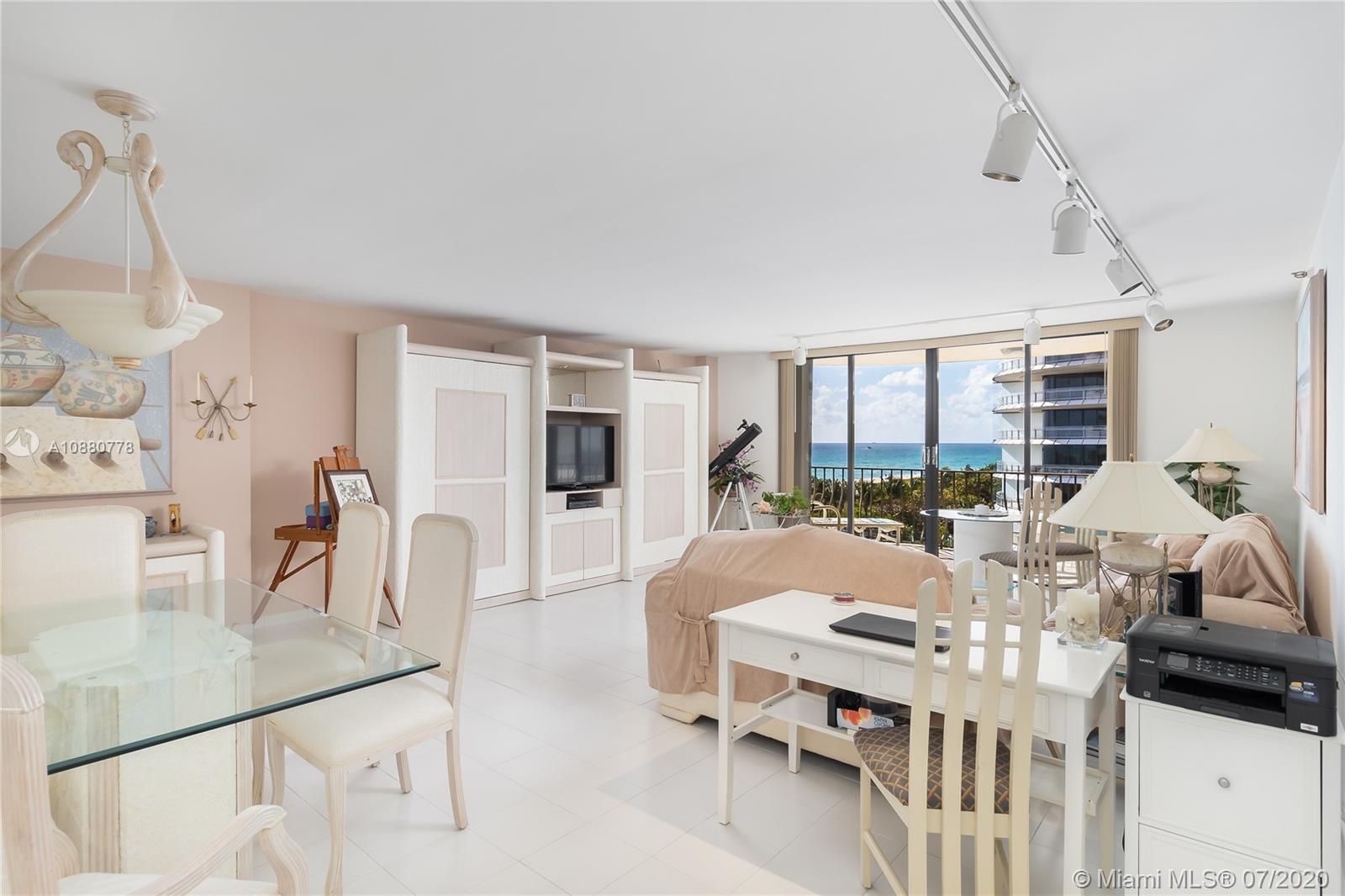 8777 Collins Avenue, Unit 611 Surfside, FL 33154 - Photo 5 of 22 a living room with furniture a large window and a chandelier