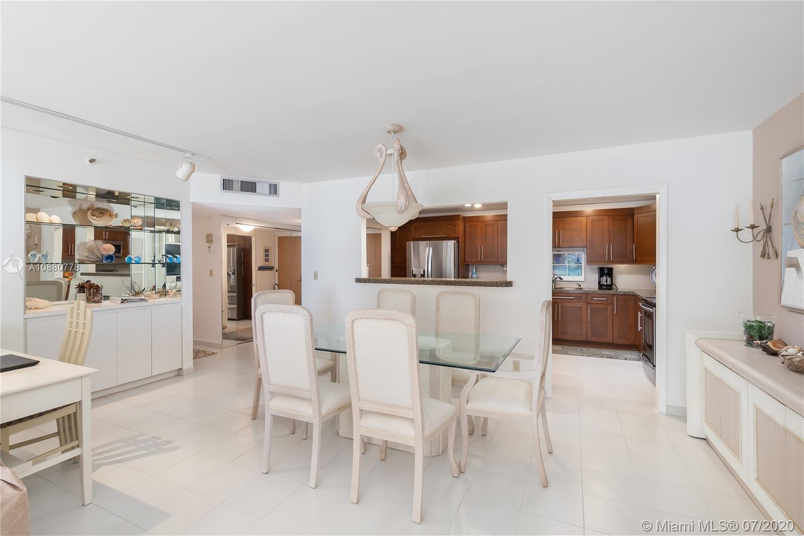 8777 Collins Avenue, Unit 611 Surfside, FL 33154 - Photo 7 of 22 a living room with furniture a flat screen tv and kitchen view