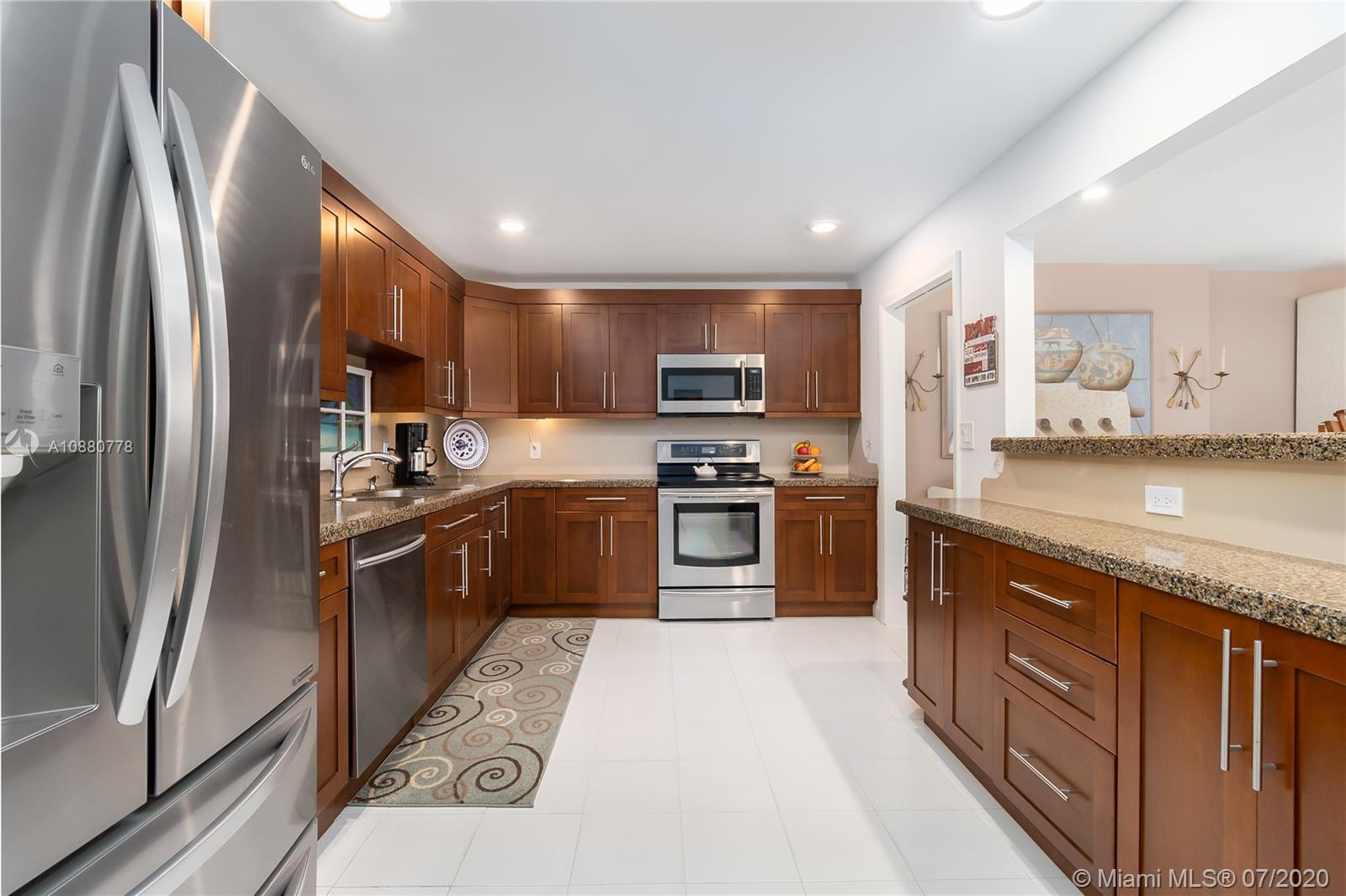 8777 Collins Avenue, Unit 611 Surfside, FL 33154 - Photo 9 of 22 a kitchen with stainless steel appliances granite countertop a refrigerator a stove a sink and a microwave