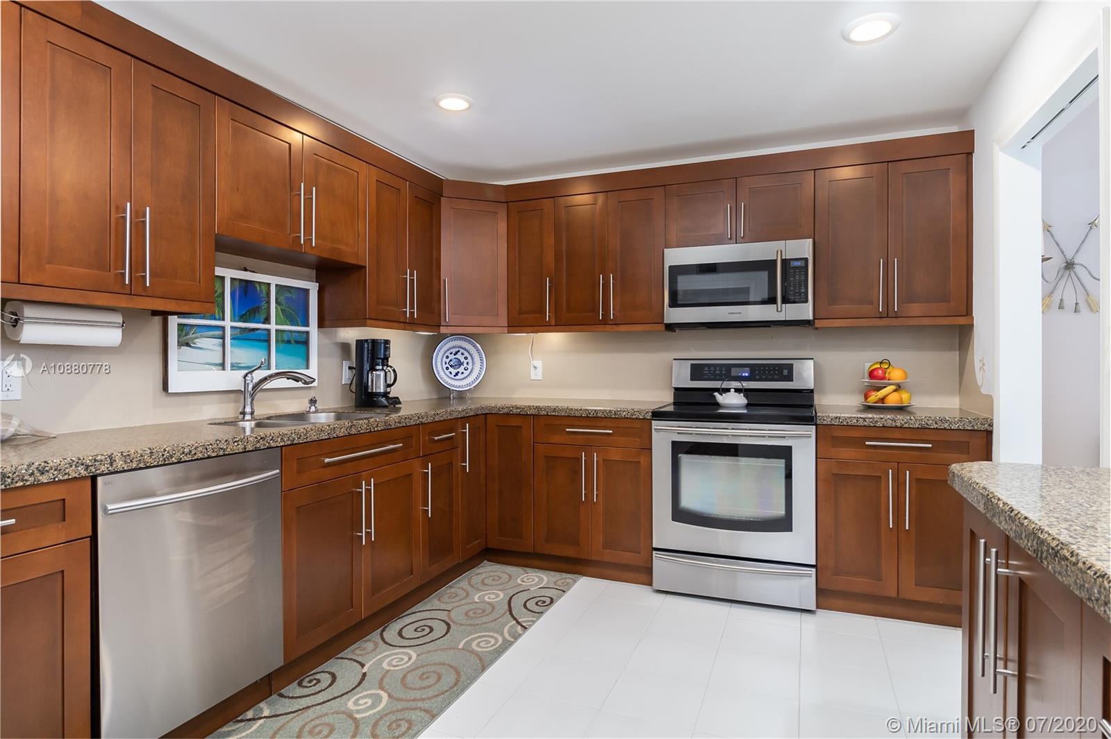 8777 Collins Avenue, Unit 611 Surfside, FL 33154 - Photo 10 of 22 a kitchen with granite countertop a stove top oven microwave and cabinets