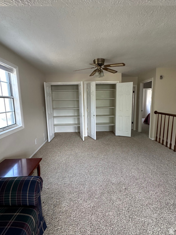 254 Meadow Lane Centerville, UT 84014 - Photo 25 of 34 Carpeted interior space featuring two built-in storage closets with bi-fold doors, a ceiling fan, and a window providing natural illumination