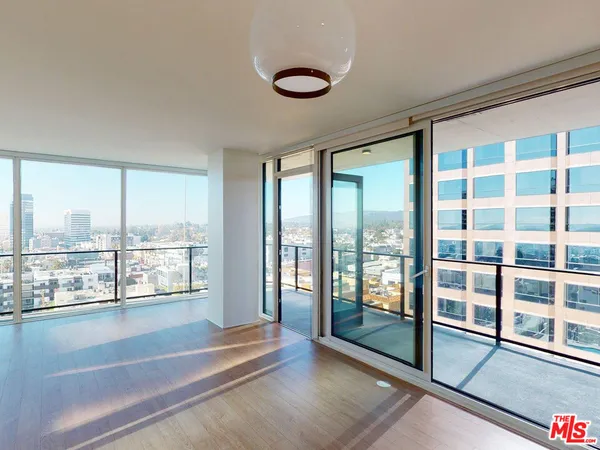 a view of an empty room with wooden floor and windows