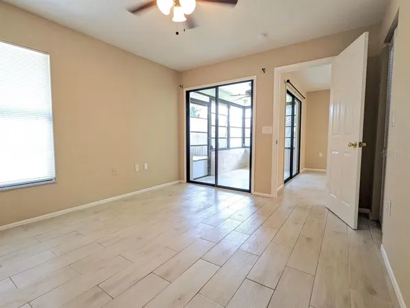 an empty room with windows and chandelier fan