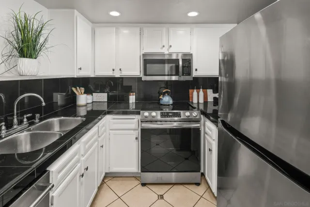 a kitchen with stainless steel appliances granite countertop a stove a refrigerator and a sink