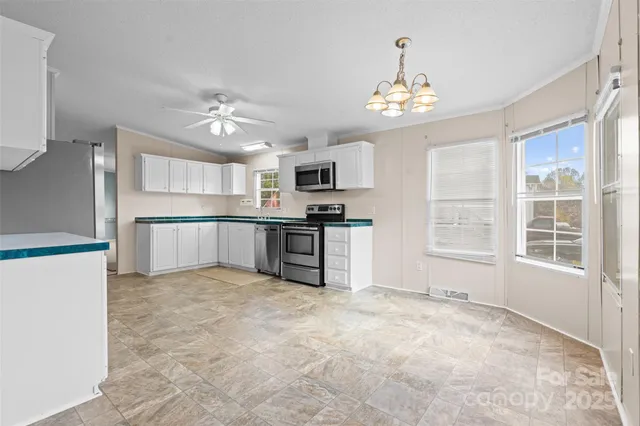 an empty room with windows and chandelier fan