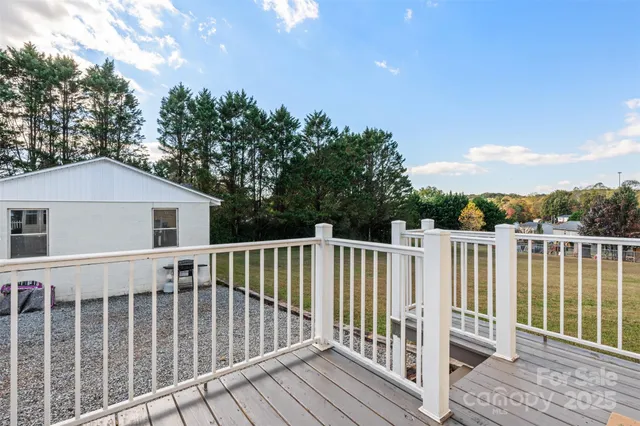 a view of a white house with a big yard and large trees