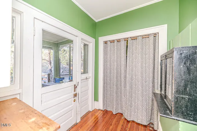 a view of a hallway with wooden floor and a bathroom