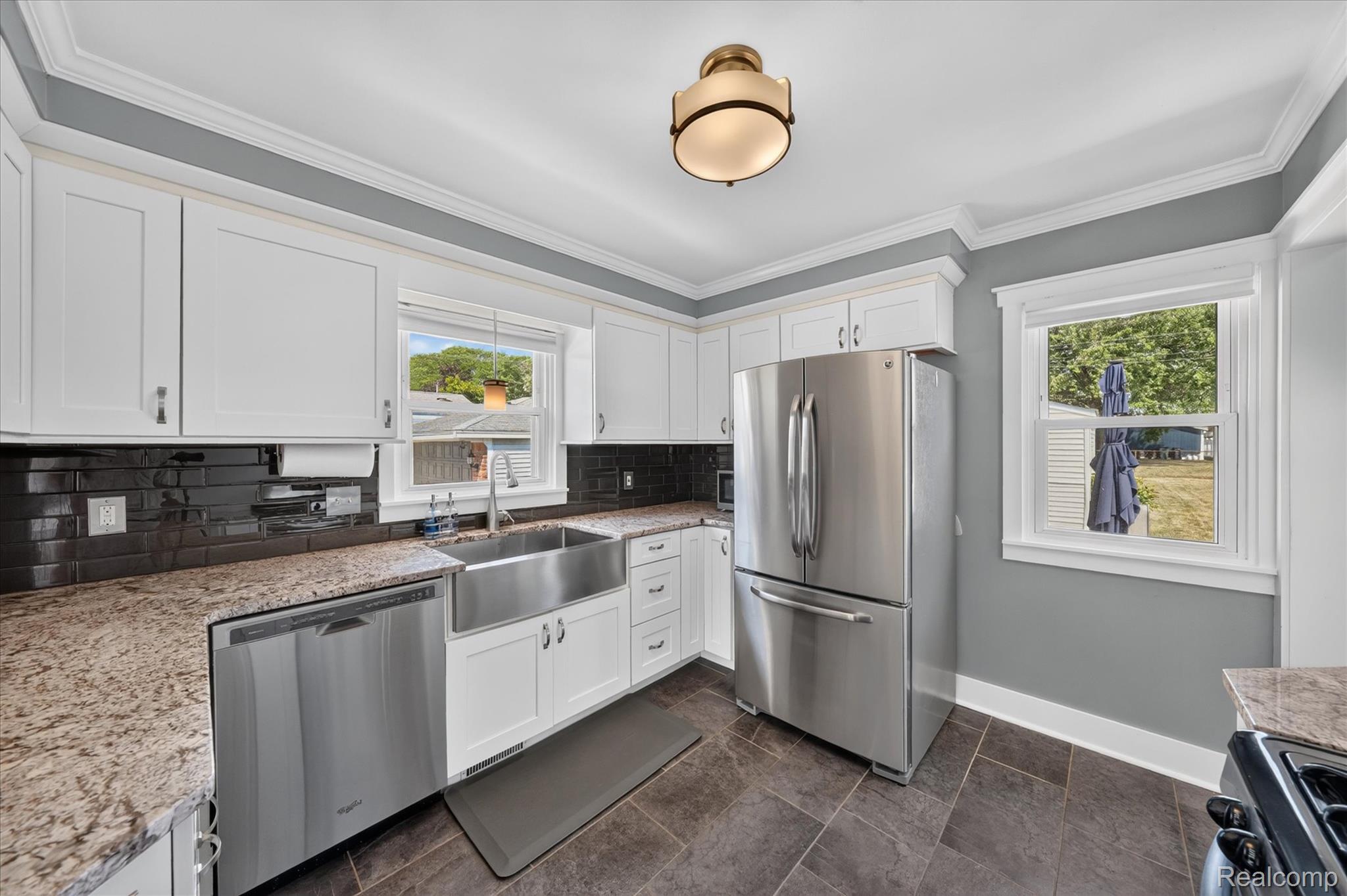 4112 Durham Road Royal Oak, MI 48073 - Photo 10 of 38 White shaker-style cabinetry, granite countertops, stainless steel appliances, farmhouse sink, and dark tiled flooring