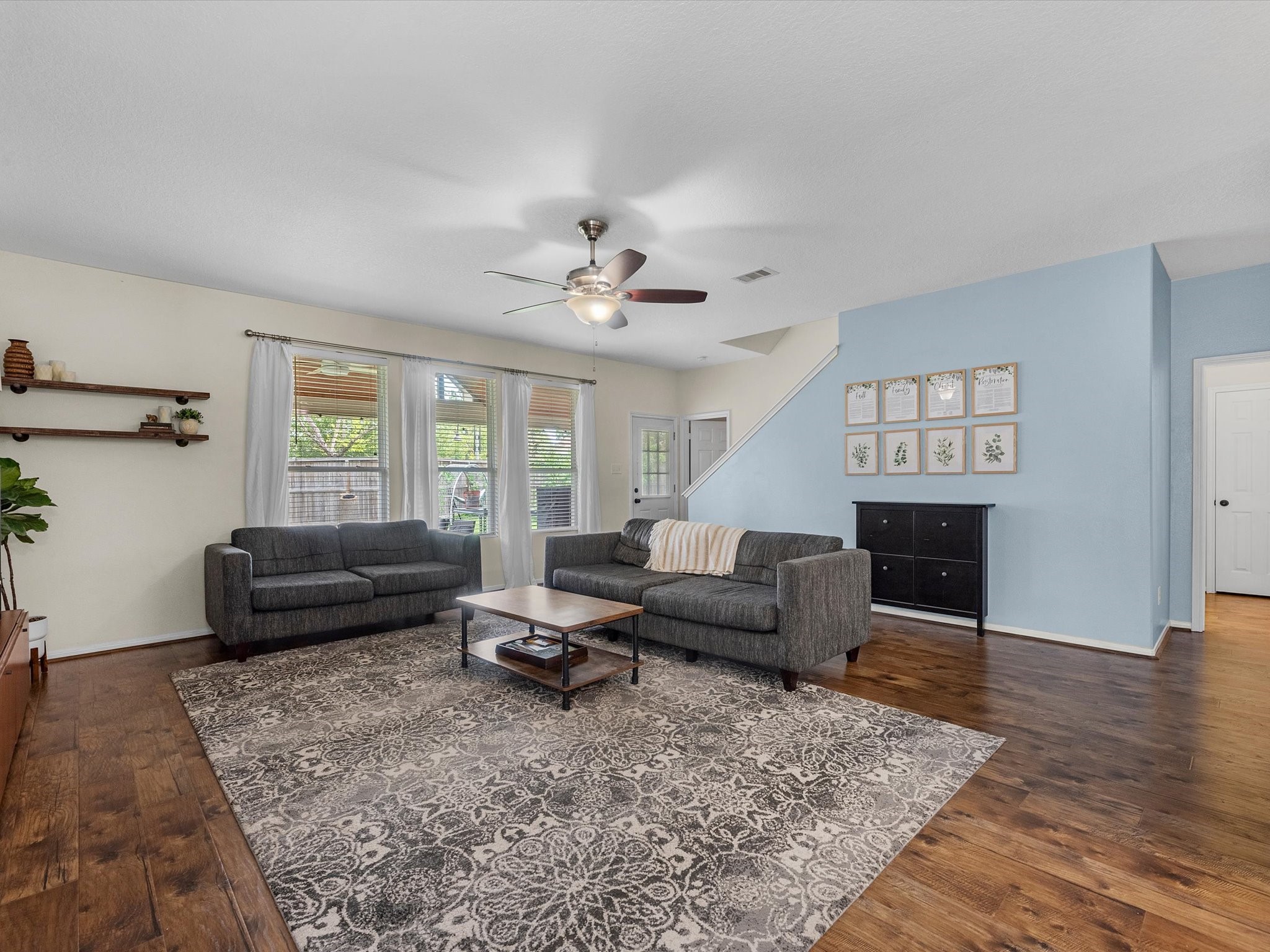 22422 Lamaster Lane Spring, TX 77373 - Photo 5 of 35 The living room features warm laminate flooring and an abundance of natural light streaming in through the glass doors and windows.