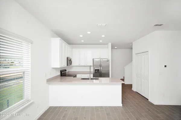 a room with kitchen island a sink wooden floor and a large window