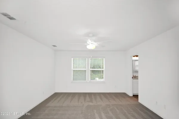 an empty room with a ceiling fan and a window
