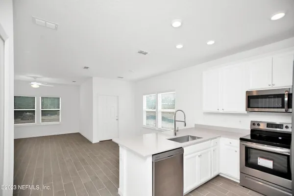 a kitchen with stainless steel appliances granite countertop a sink and a stove top oven with wooden floor