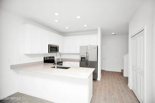 a room with stainless steel appliances a sink a microwave a refrigerator and cabinets