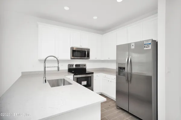 a kitchen with stainless steel appliances granite countertop a refrigerator a stove a sink and a microwave