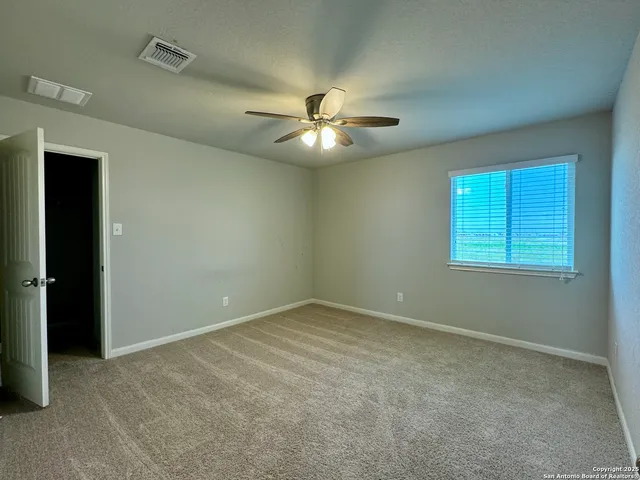 an empty room with windows and fan