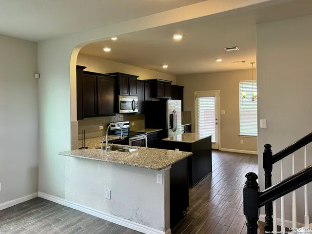 a kitchen with stainless steel appliances a sink a stove a microwave a refrigerator and cabinets