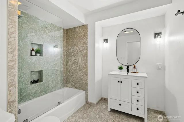a bathroom with a bathtub a mirror a sink and vanity