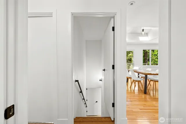 a view of a hallway with wooden floor and a bathroom