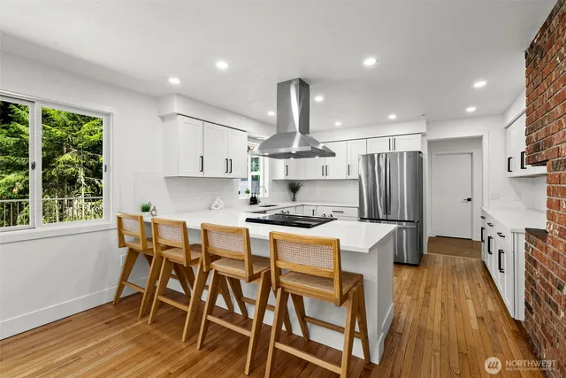 a kitchen with stainless steel appliances a dining table chairs stove refrigerator and wooden floor