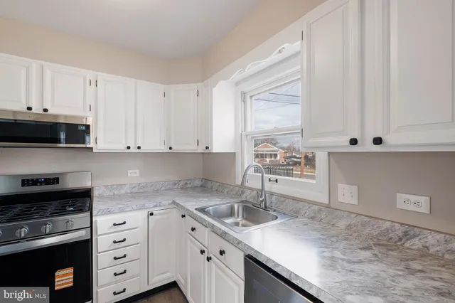 a kitchen with granite countertop a sink a stove and cabinets