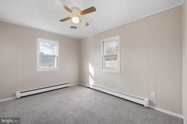 an empty room with windows and fan
