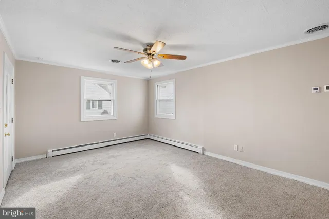 an empty room with windows and chandelier fan