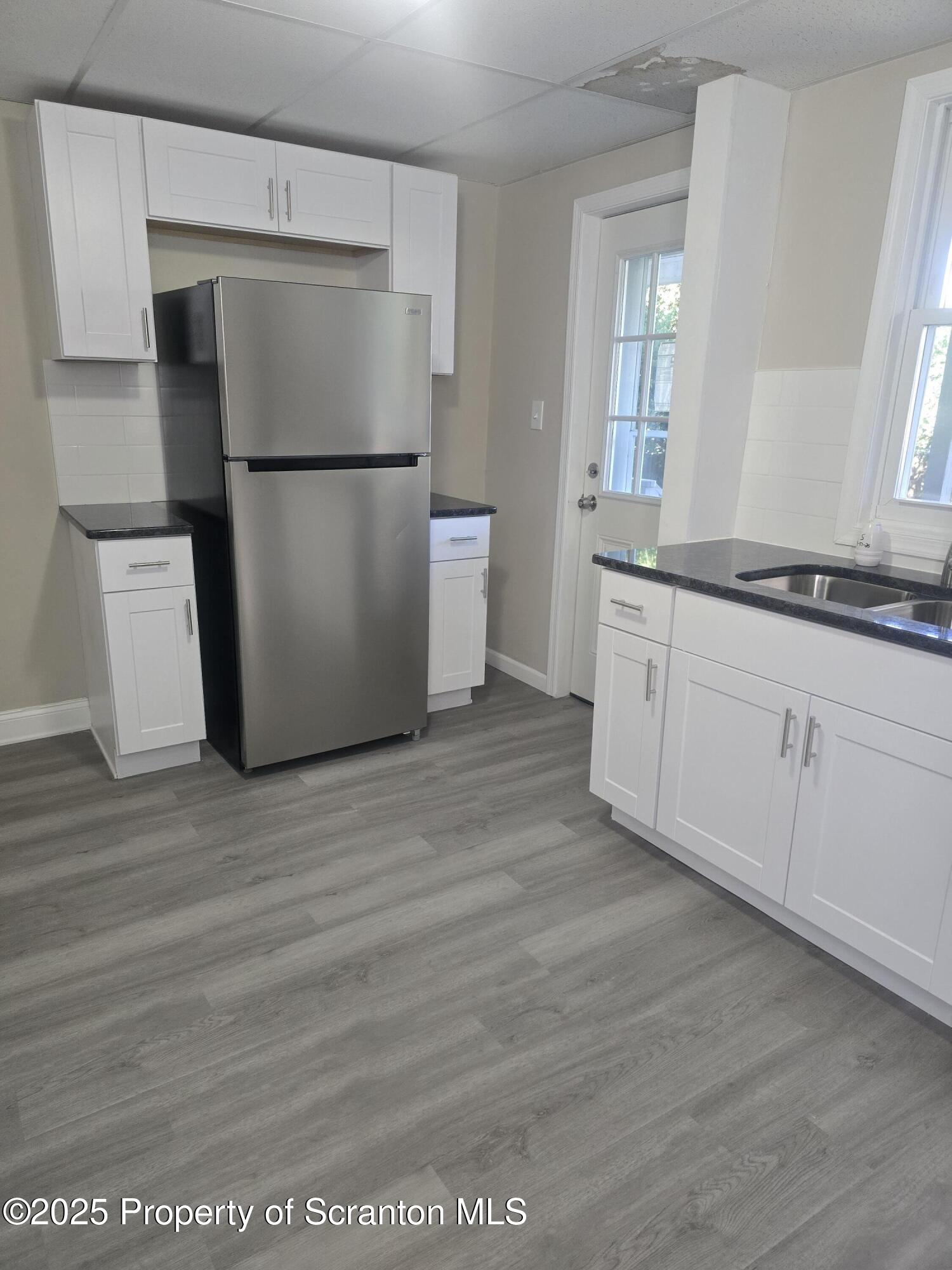 323 Larch Street Scranton, PA 18509 - Photo 4 of 18 a kitchen with granite countertop a refrigerator a sink and white cabinets