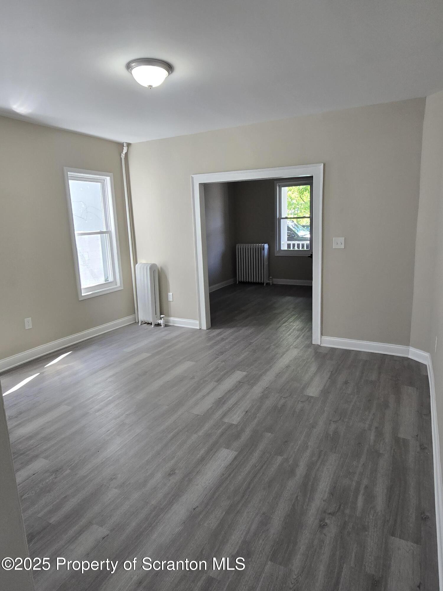 323 Larch Street Scranton, PA 18509 - Photo 7 of 18 an empty room with wooden floor and windows