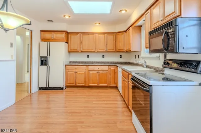 a kitchen with stainless steel appliances granite countertop a refrigerator a sink dishwasher and a stove