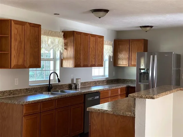 a kitchen with granite countertop a refrigerator and a sink