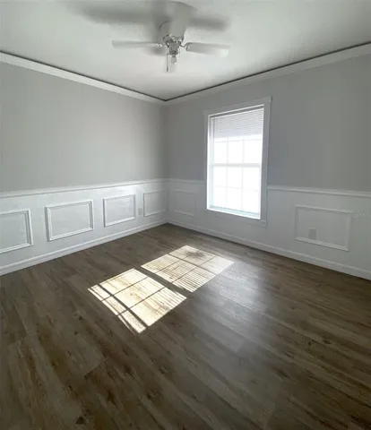 an empty room with wooden floor fan and windows