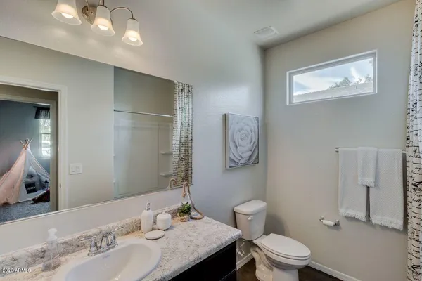 a bathroom with a granite countertop toilet a sink and a mirror