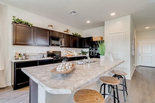 a kitchen with stainless steel appliances granite countertop a stove top oven a sink a dining table and chairs