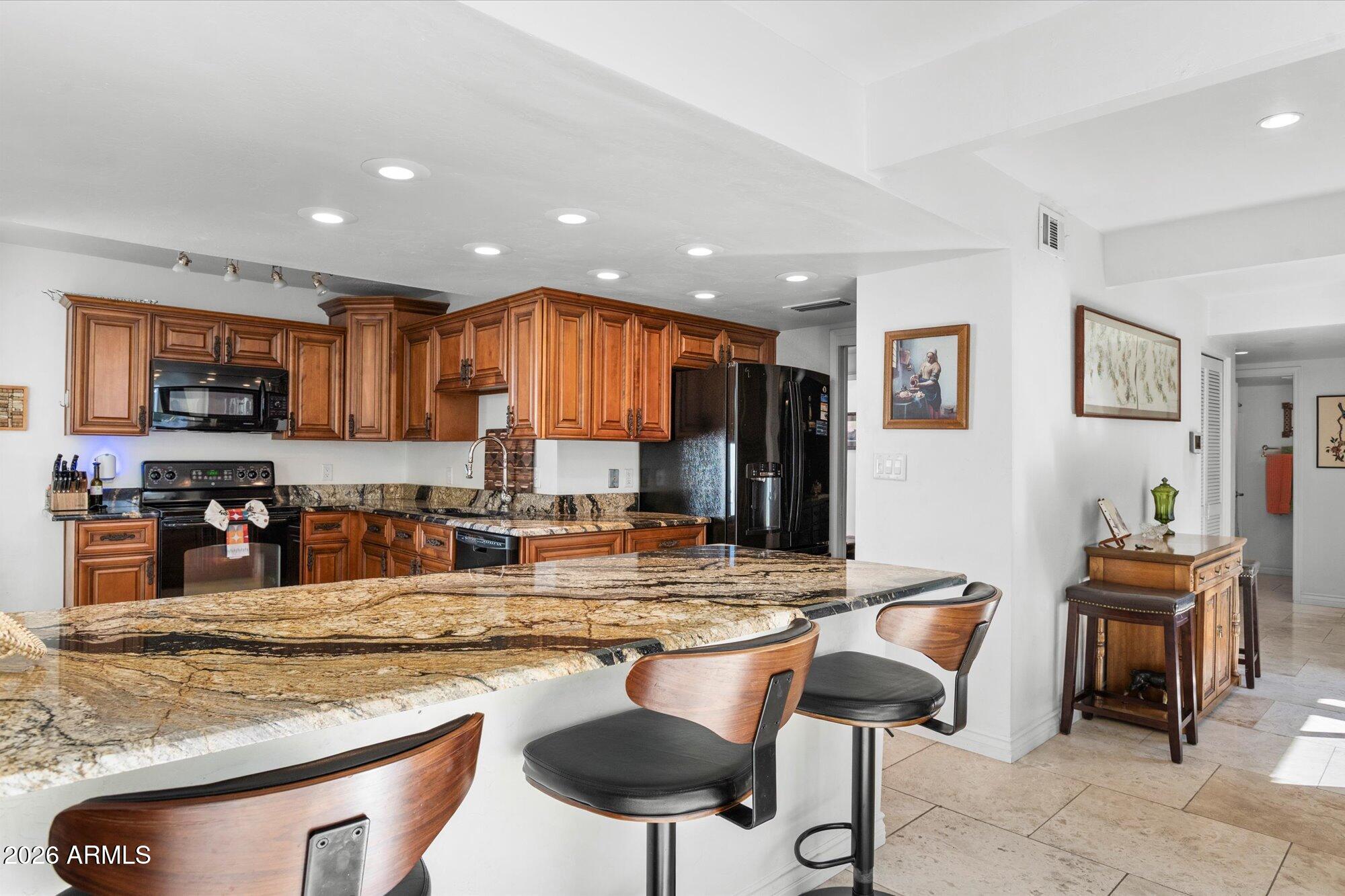 7005 North Barbados Place Phoenix, AZ 85021 - Photo 15 of 42 a kitchen with stainless steel appliances granite countertop a stove top oven a sink a dining table and chairs