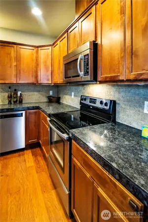 a kitchen with stainless steel appliances granite countertop a stove a sink and a microwave