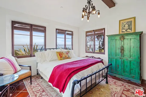 a bedroom with a bed a mirror and a window