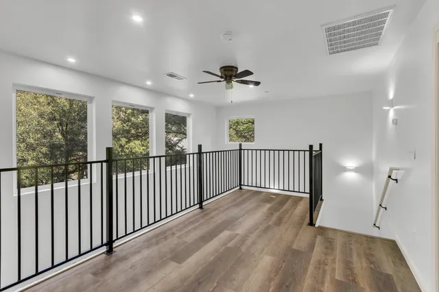 an empty room with wooden floor closet and windows