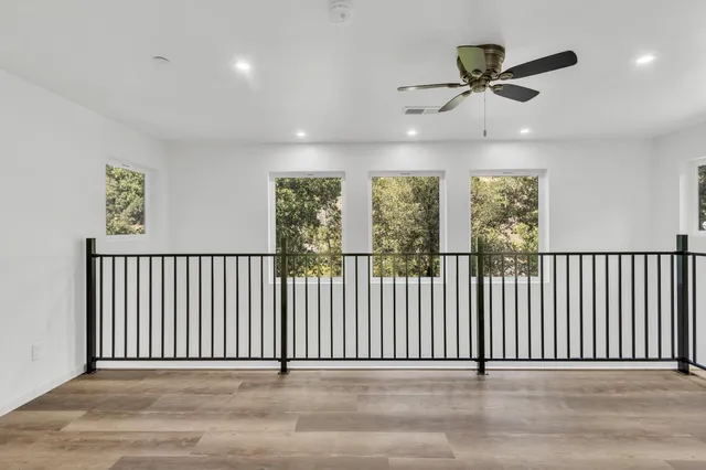 an empty room with wooden floor cabinet and windows