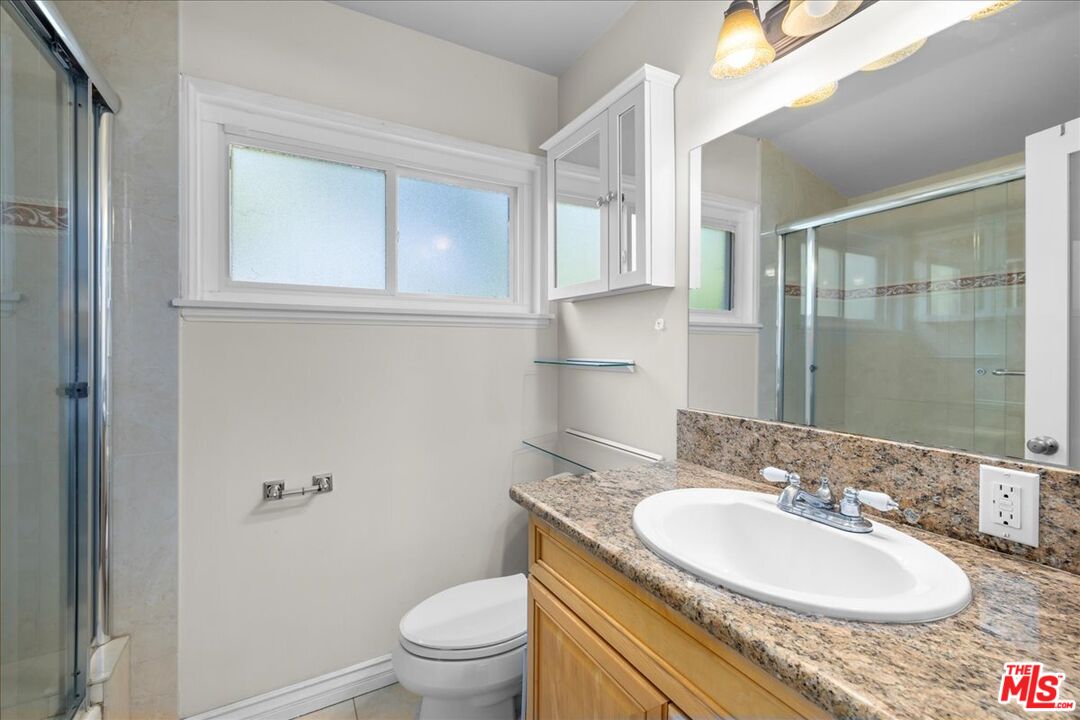 6867 Apperson Street Tujunga, CA 91042 - Photo 21 of 54 a bathroom with a granite countertop sink a toilet and a mirror