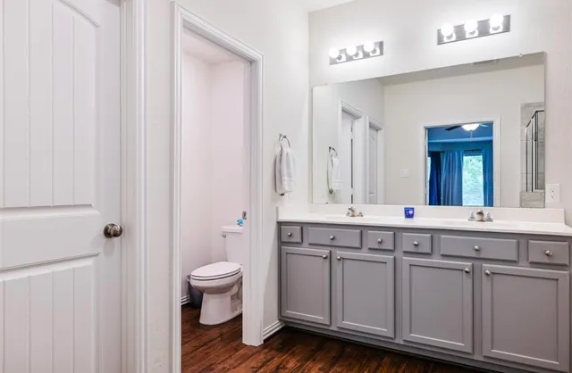 a spacious bathroom with a double vanity sink a mirror and a toilet