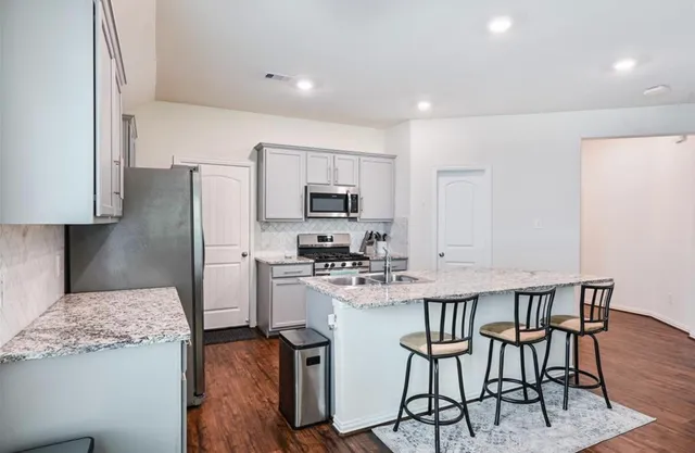 a kitchen with stainless steel appliances granite countertop a kitchen island hardwood floor and a refrigerator